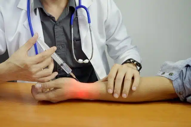 doctor giving patient joint injection on his wrist