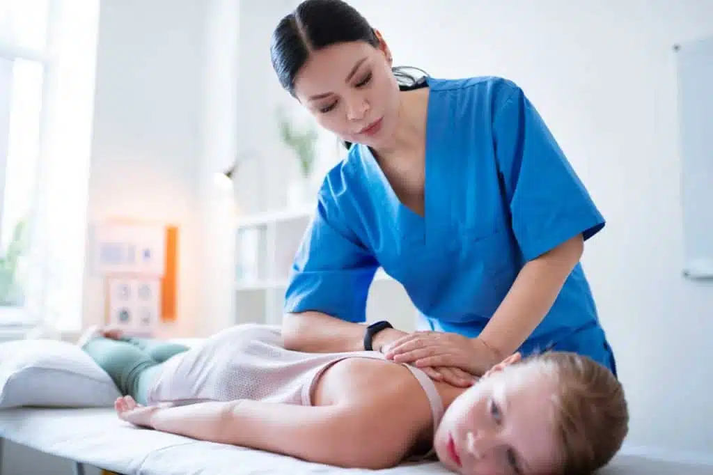 Chiropractor is doing some chiropractic adjustment to a kid patient