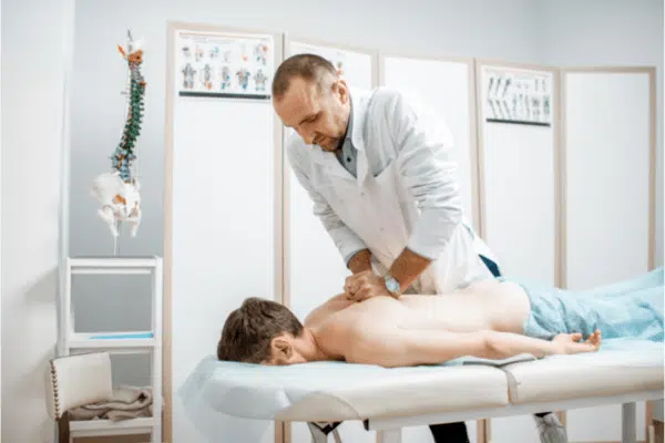 Male doctor chiropractor doing some chiropractic adjustment to the senior patient.