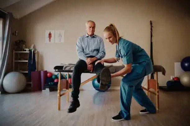 Physiotherapist helping a senior patient with his physical therapy treatment.