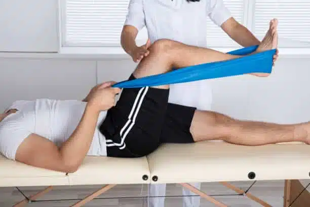 Physiotherapist Helping Patient While Stretching His Leg.